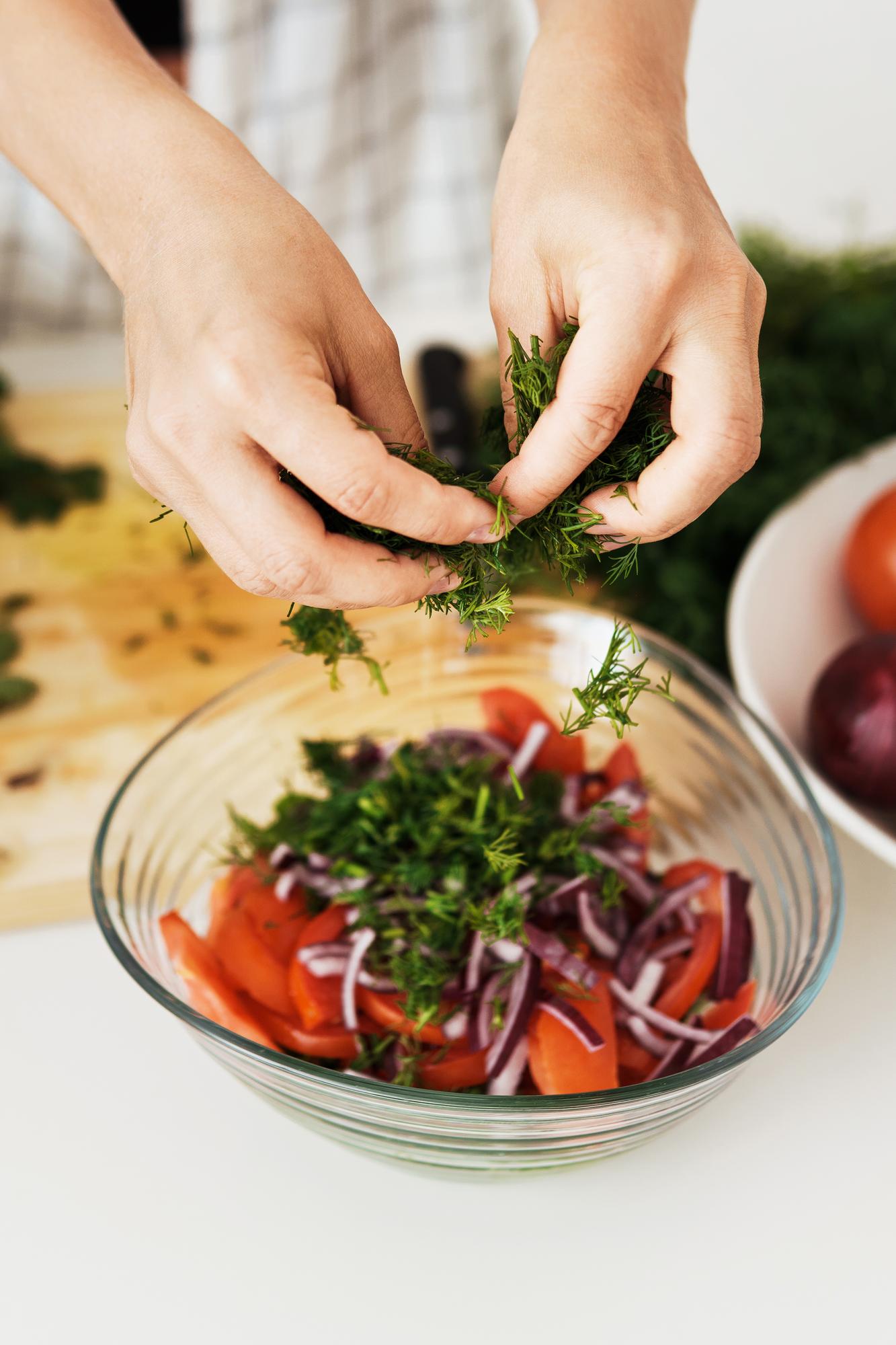 mână care pregătește o salată cu ierburi proaspete